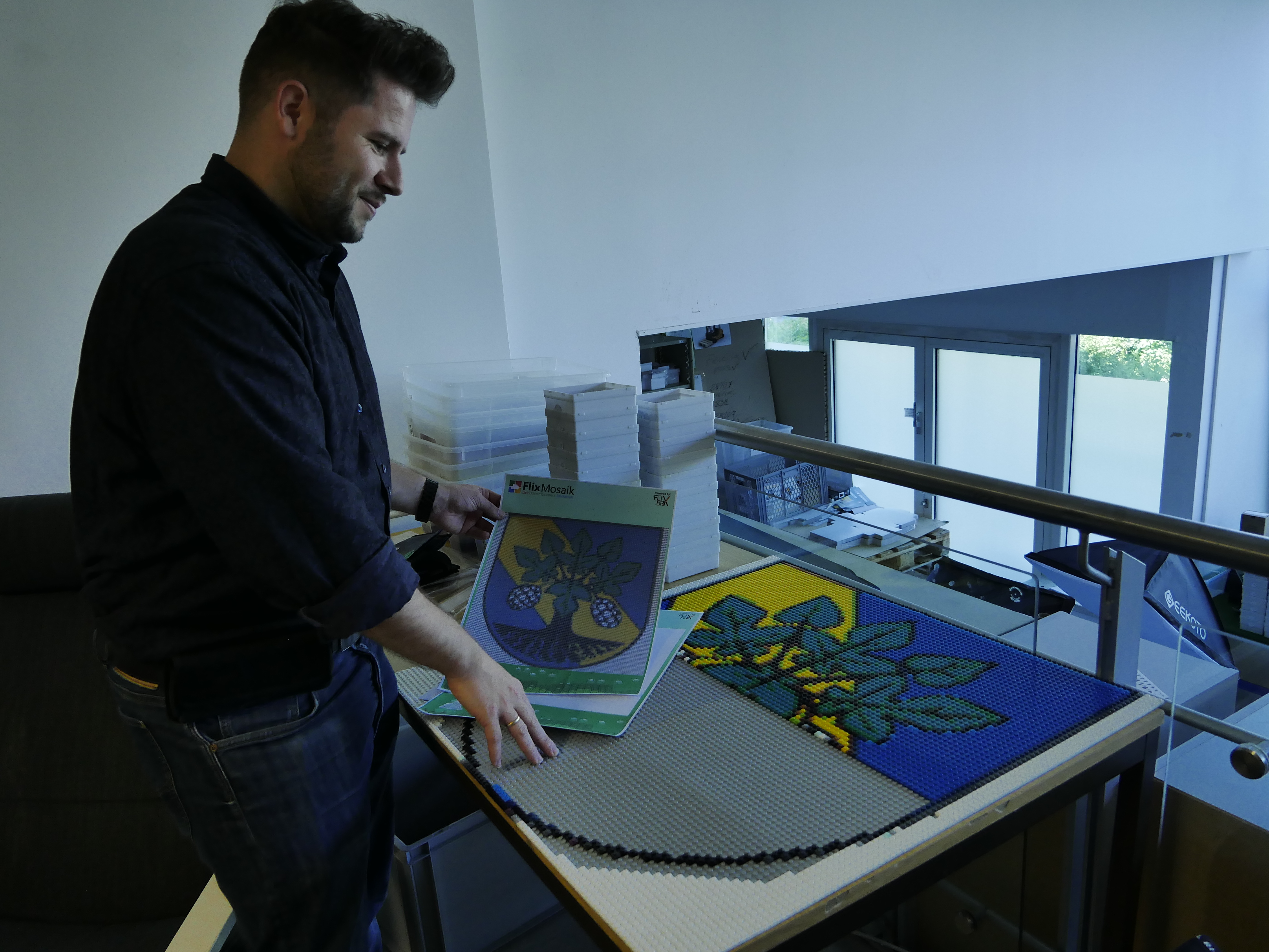 Sebastian Groth, Geschäftsführer von Flix-Brix, zeigt das Wappen von Erkner, welches gerade aus kleinen Lego-Teilen in Form eines Mosaiks erstellt wird