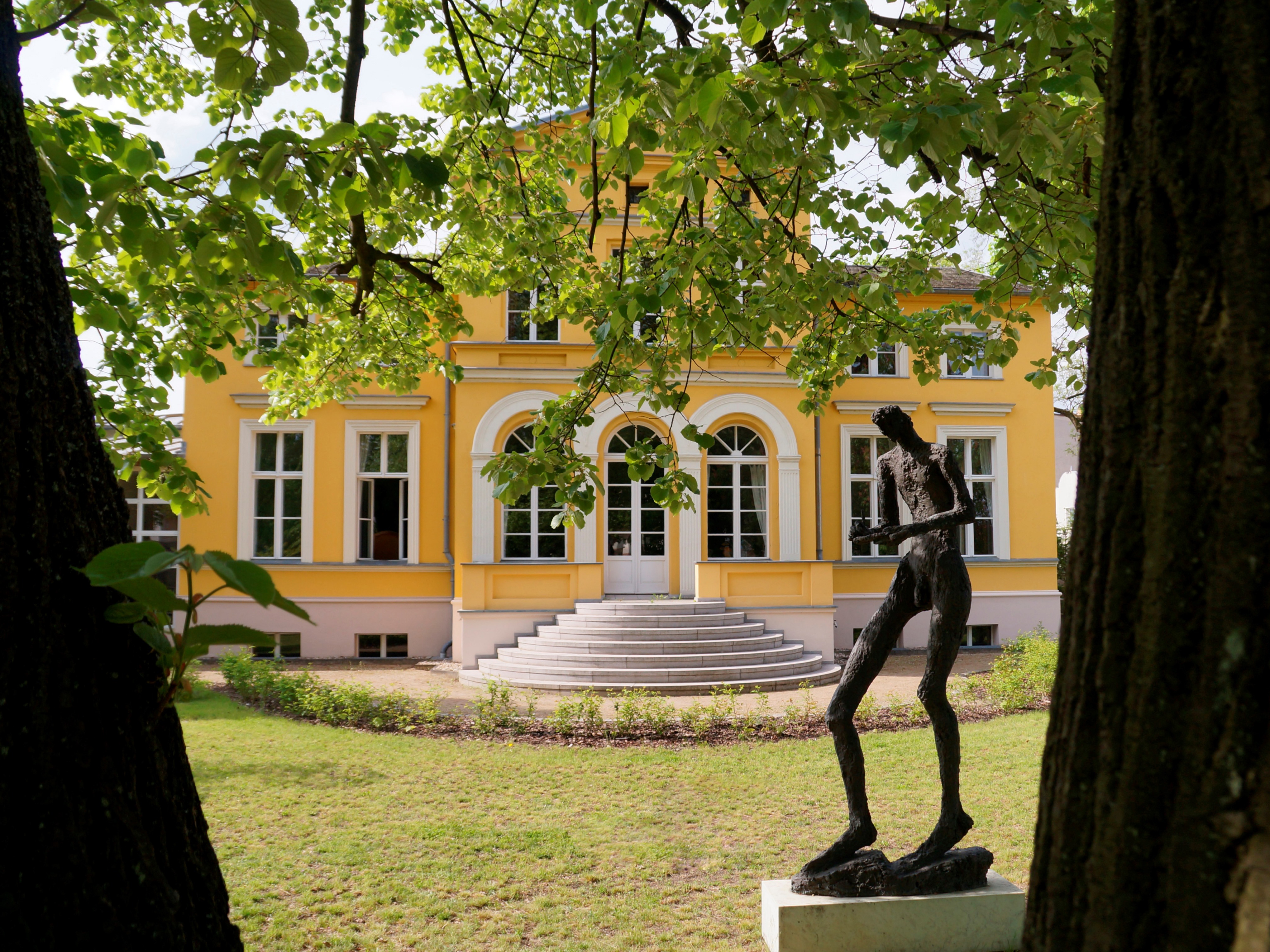Farbenfrohe gelbe Villa Lassen mit Metall-Skulptur aktuell